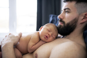 father lay on bed with his newborn baby son lying 
