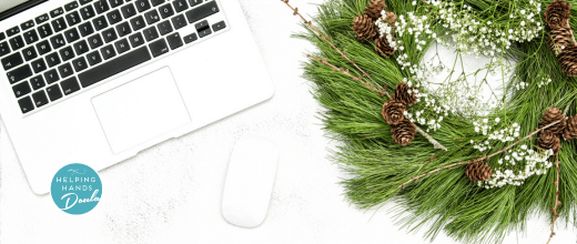 Desk with a laptop, computer mouse and a Christmas wreath.