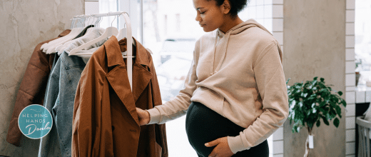 Pregnant woman shopping for maternity clothes. She is wearing a loose fitted cream sweater, and black maternity leggings.