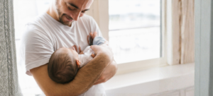 proud dad holding his newborn and smiling