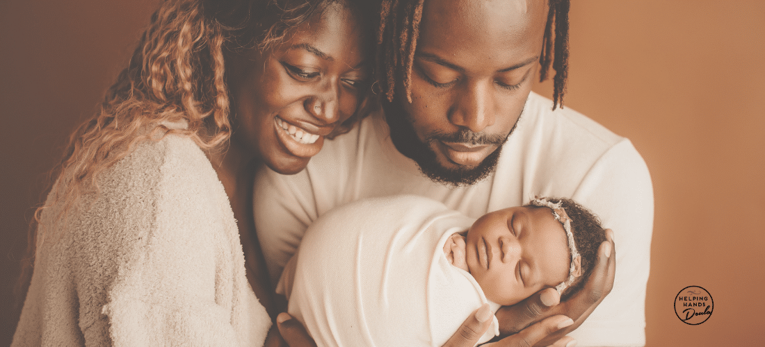Image of new mother and father holding and looking fondly at their newborn baby girl wrapped in a swaddle
