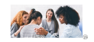 A group of supportive women surrounding a pregnant mother offering encouragement and comfort, warm natural light, documentary lifestyle photography.