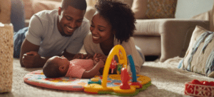 newborn baby playing at home with parents on activity mat