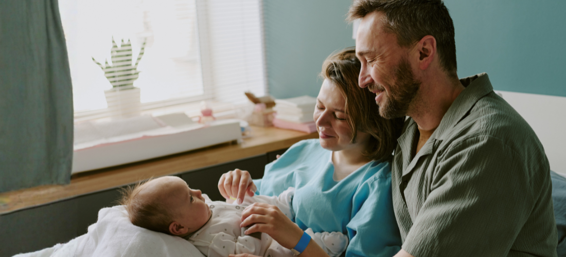 new parents holding newborn baby in hospital bed